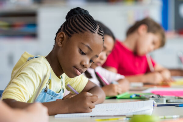 Cute,Pupil,Writing,At,Desk,In,Classroom,At,The,Elementary